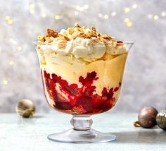 a dessert in a glass bowl with whipped cream and fruit toppings on the side