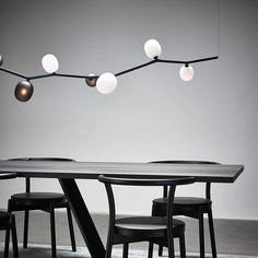 a table with four chairs and lights hanging from it's ceiling in an empty room