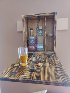 a bottle and glass sitting on top of a wooden shelf next to a corkscrew