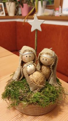 two cloth nativity figures sitting on top of a moss covered basket with a star