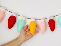 a hand is holding a small felt christmas ornament on a string with colored stockings hanging from it