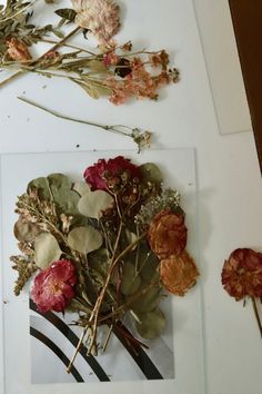 dried flowers sit on top of a white table