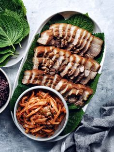 some meat and vegetables are in bowls on a table next to other foods that have been cut into smaller pieces