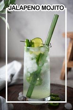 a tall glass filled with ice, lime and cucumber on top of a wooden table