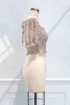 A sweet and simple versatile wardrobe staple perfect for summer, the Emily cropped blouse features a smocked elastic bodice, short sleeves with smocked cuffs, a cropped hem, and a pretty floral-print chiffon. Please Note- This item is final sale only. . Details: S: Bust 34", Length 18" M: Bust 36", Length 18.5" L: Bust 38", Length 19" Length Measured from Shoulder Unlined Material: 100% Polyester Facing: 100% Rayon Imported Gentle Wash Cold / Line Dry Fitted Smocked Top With Short Sleeves, Summer Short Sleeve Blouse With Elastic Shoulders, Summer Blouse With Elastic Shoulders And Short Sleeves, Spring Short Sleeve Smocked Stretch Top, Summer Short Sleeve Crop Top With Smocked Bodice, Spring Stretch Smocked Top With Short Sleeves, Summer Crop Top With Smocked Back And Short Sleeves, Summer Tops With Smocked Back And Short Sleeves, Stretch Smocked Top With Short Sleeves For Spring