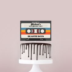 a white cake with chocolate drips and a cassette label on top that says beastie boys