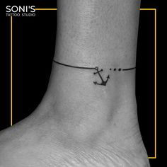 a black and white photo of a small anchor tattoo on the ankle, with an inscription that reads son's tattoo studio