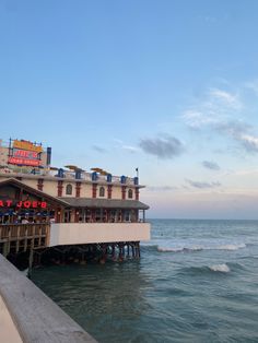 a pier with people sitting on it next to the ocean