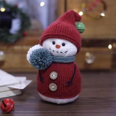 a knitted snowman doll sitting on top of a wooden table