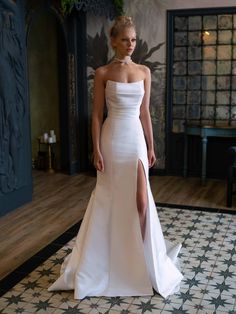 a woman in a white dress standing on a tile floor