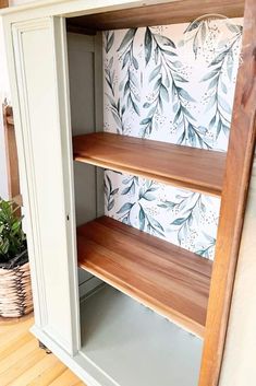 a wooden shelf with two shelves on top of it next to a potted plant