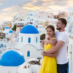 a man and woman standing on top of a building with blue domes in the background