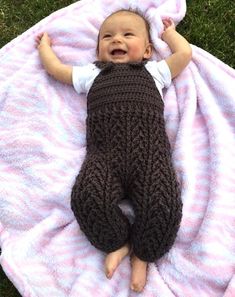 a baby laying on top of a pink blanket covered in a brown knitted sleeping bag