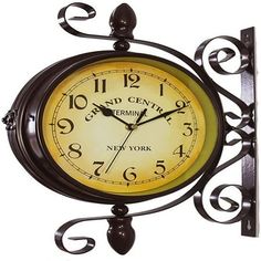 a clock that is on the side of a wall with an iron frame and scroll design