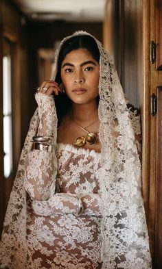 a woman wearing a veil and holding a cup in her hand while standing next to a door