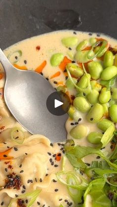 a spoon in a bowl filled with soup and veggies on top of it