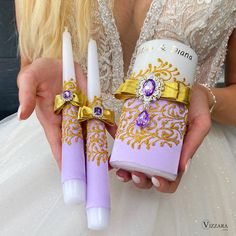 two purple and gold wedding candles are being held by a woman in a white dress