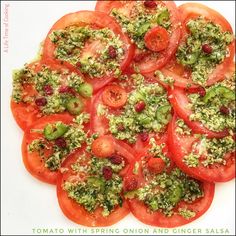 tomatoes and broccoli arranged in a circle on a white plate with the words tomato with spring onion and ginger salsa