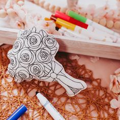 a bouquet of roses on a pillow next to markers and crayon pens in front of it