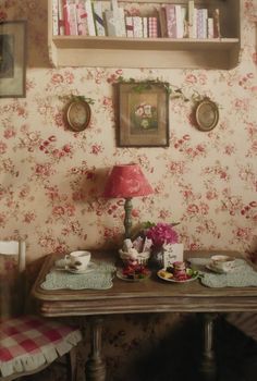 a room with a table, chair and bookshelf on the wall above it