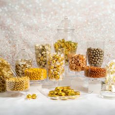 there are many different types of candies in glass containers on the table with glittery background