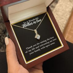 a woman's hand holding a necklace in a box with a poem on it