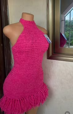 a mannequin wearing a pink dress with fringes on the bottom and neck