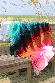 a blanket is sitting on a bench by the beach