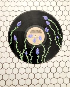 a record with flowers painted on it sitting on a tiled floor next to a wall