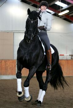 a woman riding on the back of a black horse