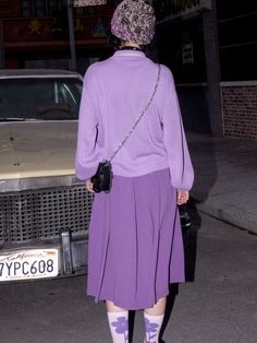 a woman in purple is walking down the street