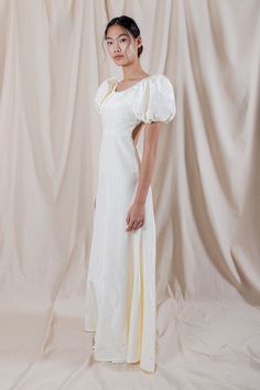 a woman standing in front of a white backdrop wearing a dress with ruffle sleeves