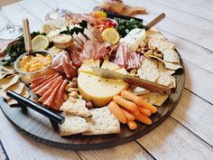 a wooden platter filled with cheese, crackers and meats