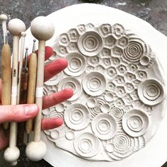 a person holding several different types of woodworking tools in front of an intricate carving