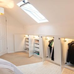 an attic bedroom with white walls and open closets