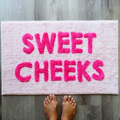 someone standing in front of a pink bath mat that says sweet cheeks on the floor