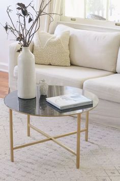 a living room with a couch, coffee table and vase filled with flowers on it