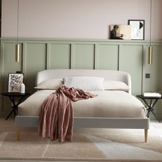 a white bed sitting in a bedroom next to a green headboard on a wall