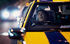 a man is sitting in the drivers seat of a yellow and blue striped car at night