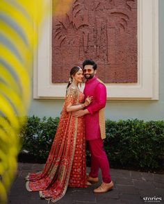 a man and woman standing next to each other in front of a building