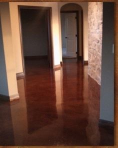 an empty room with wood floors and stone walls in the background is lit by sunlight coming through two doorways