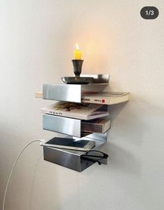 a stack of books with a candle on top of it next to a white wall