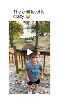 a young boy standing on top of a wooden deck next to a lake and trees