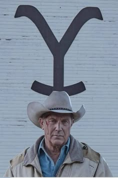 an older man wearing a cowboy hat standing in front of a building with the y on it