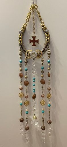 a cross hanging from the side of a wall with beads and chains attached to it