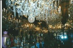 a large chandelier hanging from the ceiling in a room filled with glass vases