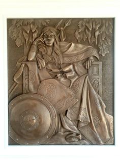 a metal plaque with a woman sitting in a chair next to a tree and shield