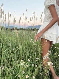 a woman is standing in the tall grass