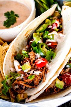 two tacos on a plate with salsa and tortilla chips