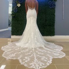 the back of a woman's wedding dress in front of a wall with flowers